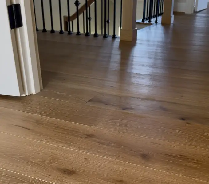Wide-plank white oak running from a bedroom doorway to the stair railing